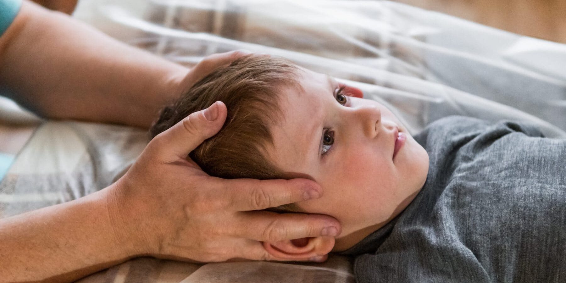 Osteopathy Treatment. Elementary age boy's forehead being manipulated by real osteopathic physician